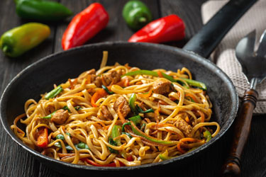 Stir fried noodles with meat and peppers in pan